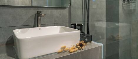 A modern bathroom with a rectangular white sink, a mirror above it, and a glass shower enclosure.
