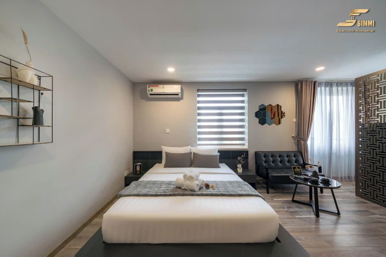 A modern hotel room with a large bed, a seating area, and a decorative wall panel.
