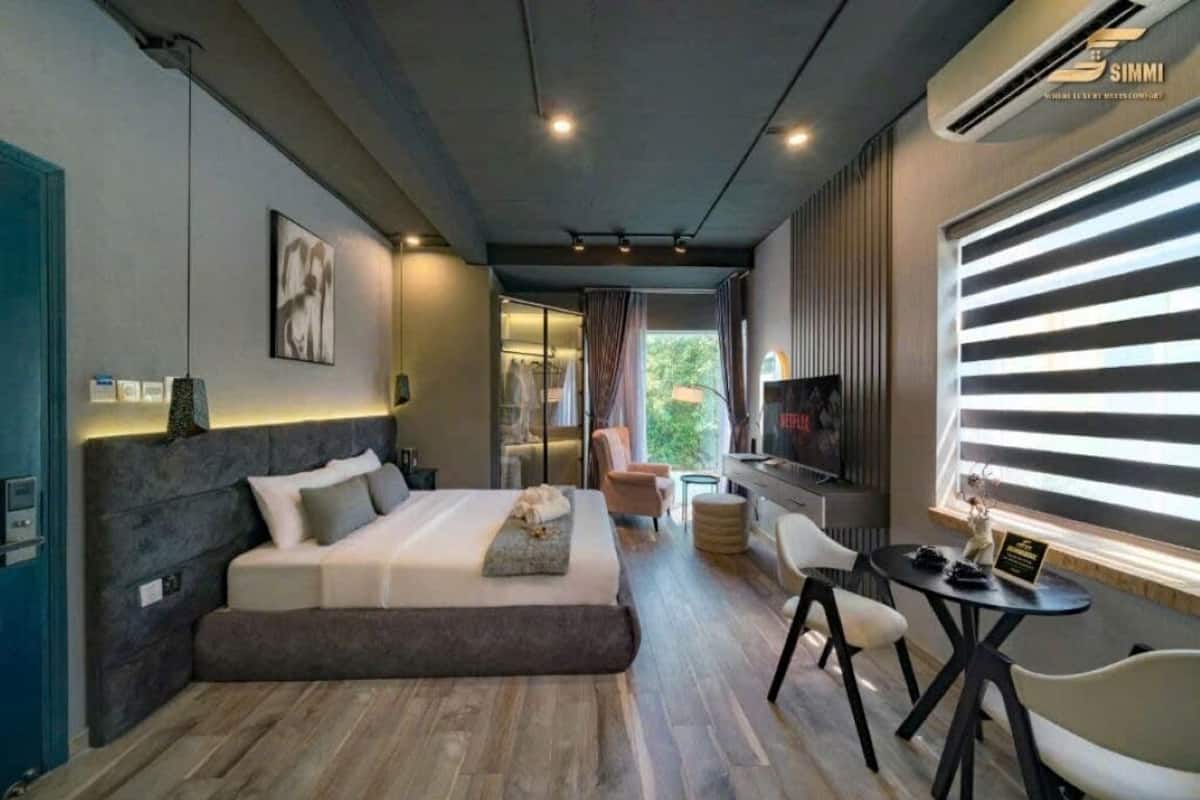 Een moderne slaapkamer met een groot bed, een televisie en een zithoek met een tafel en stoelen.