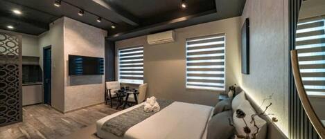 A modern hotel room with a large bed, a desk, and a seating area.