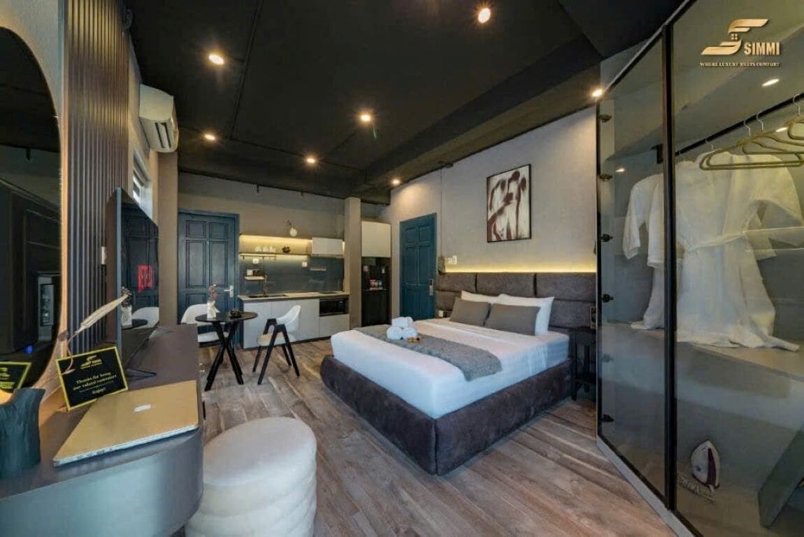 Una habitación de hotel moderna con una cama grande, un escritorio, una silla y un armario.