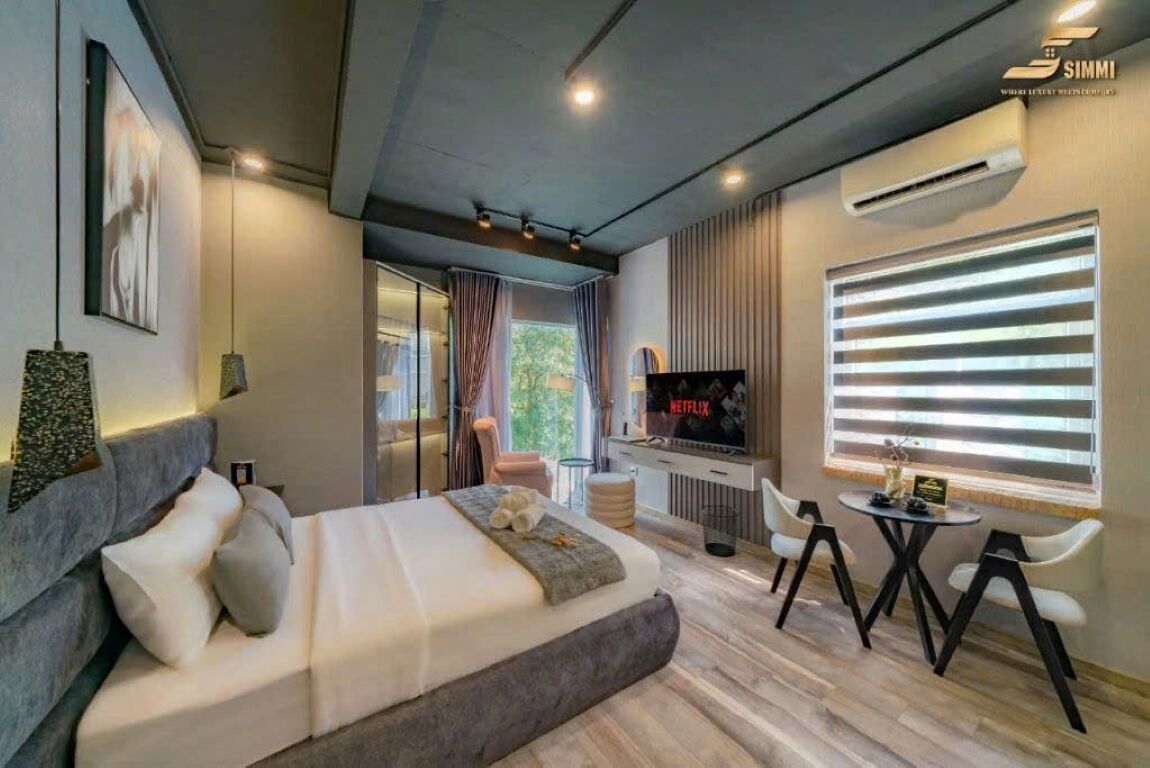Ein modernes Hotelzimmer mit einem großen Bett, einem Fernseher, einem kleinen Tisch und einer Sitzecke.