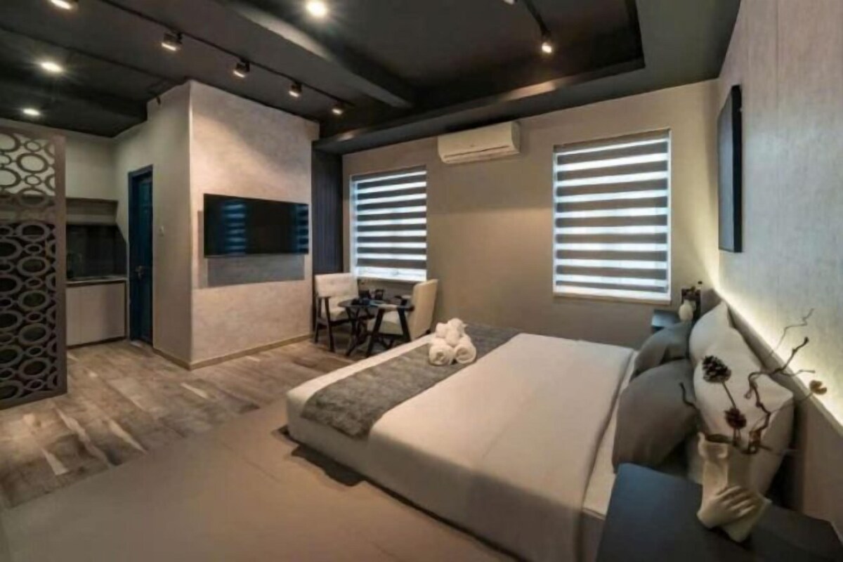 Quarto de hotel moderno com uma cama grande, uma escrivaninha e um espaço de estar.