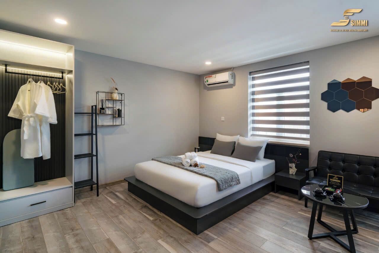 A modern bedroom with a bed, bedside table, and a seating area with a sofa and a small table.