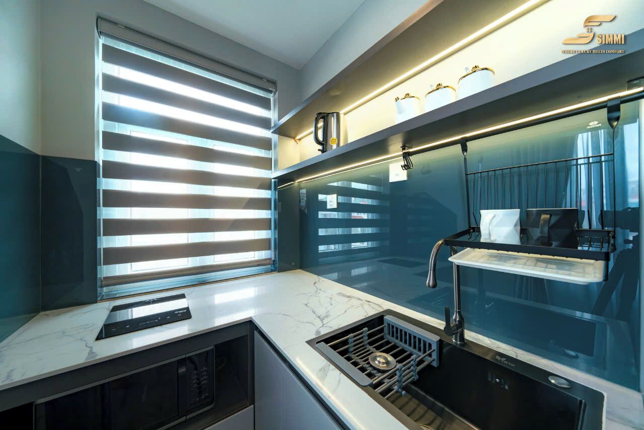 Una cocina moderna con estufa integrada, una ventana con persianas y una repisa con utensilios de cocina.