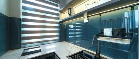 Una cocina moderna con estufa integrada, una ventana con persianas y una repisa con utensilios de cocina.