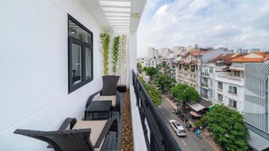 Un balcon agrémenté de meubles en osier, une vue sur le paysage urbain et un ciel dégagé.