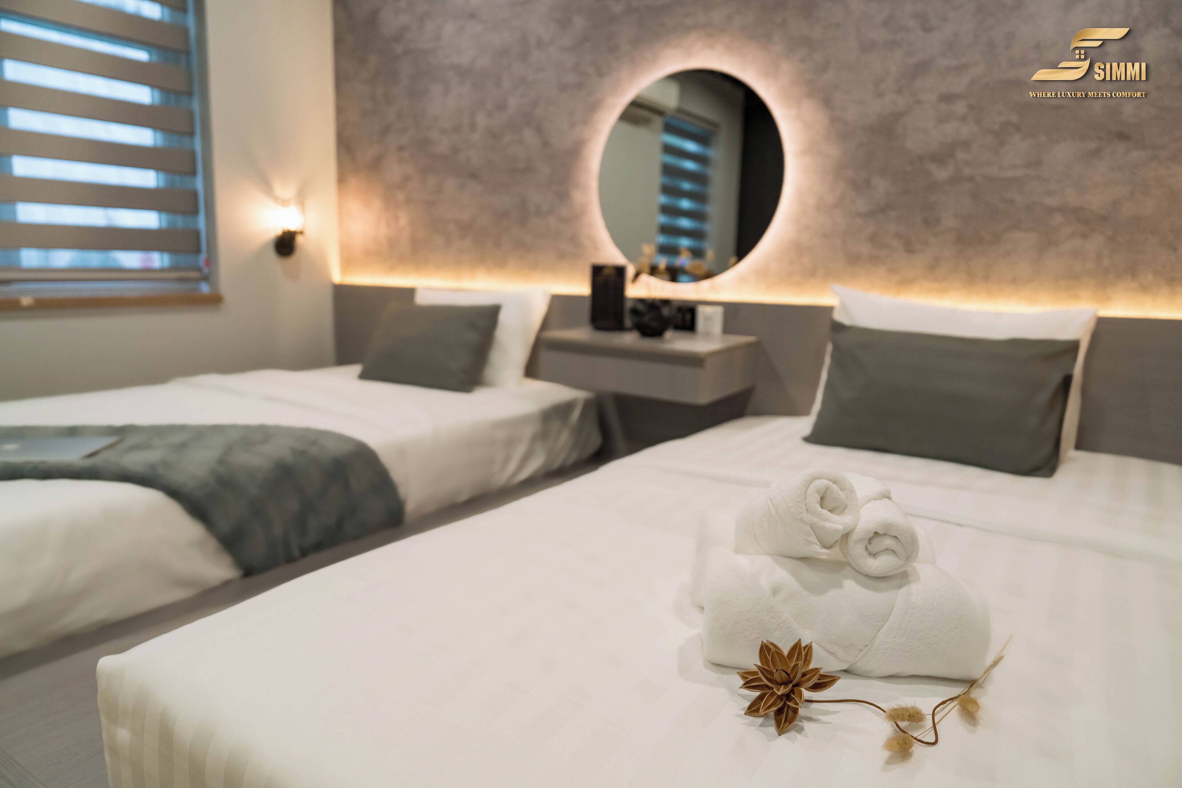 Una habitación de hotel con dos camas, un espejo redondo y una mesita de noche.