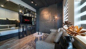 Un salon moderne avec un grand téléviseur à écran plat, un canapé, une table basse et une plante décorative.