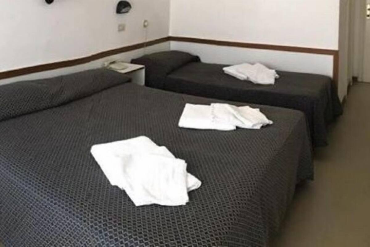 A hotel room with two beds, a desk, and a chair.