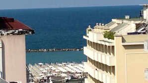 A coastal hotel with a view of the sea, featuring balconies and a beach area with umbrellas. - Hotel Marea (Cattolica)