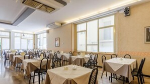 A dining area with multiple tables and chairs, large windows, and a ceiling with a ventilation system. - Hotel Marea (Cattolica)