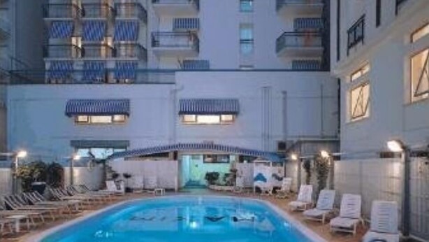 A hotel with a swimming pool, lounge chairs, and balconies. - Hotel Marea (Cattolica)