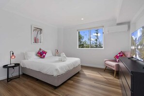 A bedroom with a bed, bedside tables, a chair, a dresser, a window, and a wall-mounted air conditioner. - The Seabreeze Sanctuary (WOORIM)