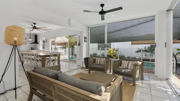 A spacious living area with a large window, a ceiling fan, and a dining area with white chairs. - The Seabreeze Sanctuary (WOORIM)