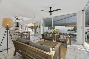A spacious living area with a large window, a ceiling fan, and a dining area with white chairs. - The Seabreeze Sanctuary (WOORIM)