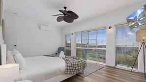 A bedroom with a bed, a desk, a chair, a ceiling fan, and a TV. - The Seabreeze Sanctuary (WOORIM)