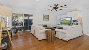 A modern living room with a sofa set, a television, and a ceiling fan. - The Seabreeze Sanctuary (WOORIM)