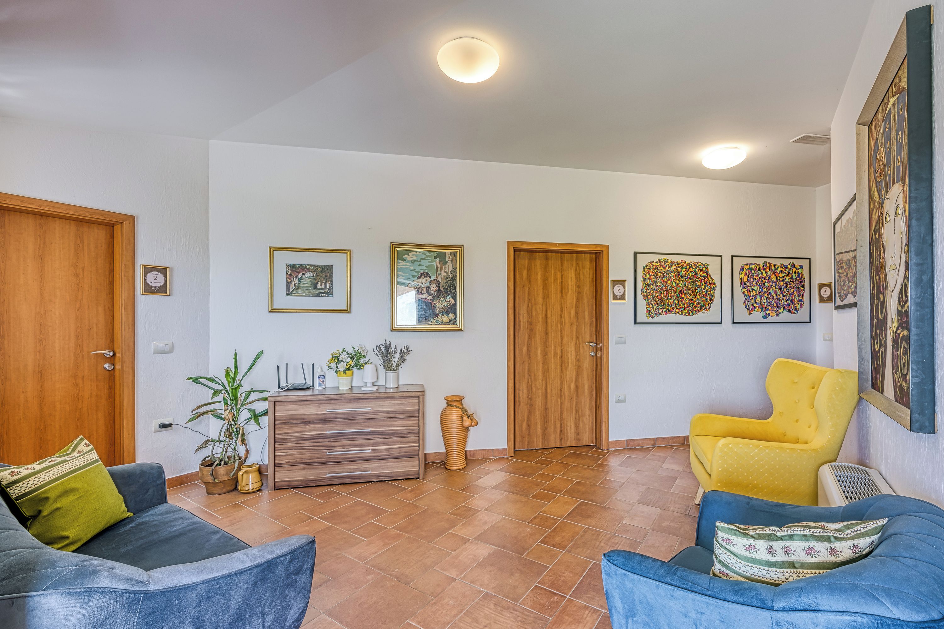 A spacious living area with two sofas, a wooden cabinet, and a potted plant.