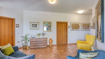 A spacious living area with two sofas, a wooden cabinet, and a potted plant.