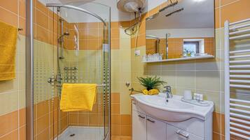 A bathroom with a glass shower enclosure, a white sink, and a mirror above it.