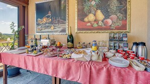 A breakfast buffet with various food items, a bottle of wine, and two paintings on the wall. - Grad Inn Room Marjoram With Pool (Koper)
