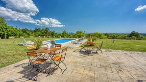 A poolside area with lounge chairs, a wooden table, and a view of the pool and surrounding greenery. - Grad Inn Room Marjoram With Pool (Koper)