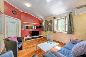 A modern living room with a flat-screen TV, a sofa, a coffee table, and a red accent wall.