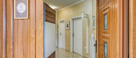 Un pasillo con paneles de madera, suelo de baldosas y una puerta con detalles decorativos.