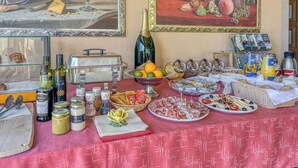 Une table dressée avec de la nourriture, des boissons et des condiments, notamment une bouteille de vin, des pots et un panier de fruits.