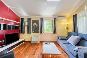 Un soggiorno con TV a schermo piatto, un divano, un tavolino da caffè e una finestra con tende.