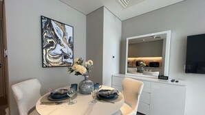 A modern dining area with a round table, chairs, a vase with flowers, and a painting on the wall.