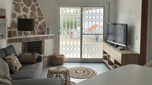 Un salon moderne avec un mur d’accent en pierre, une cheminée, un téléviseur et un canapé agrémenté de coussins.