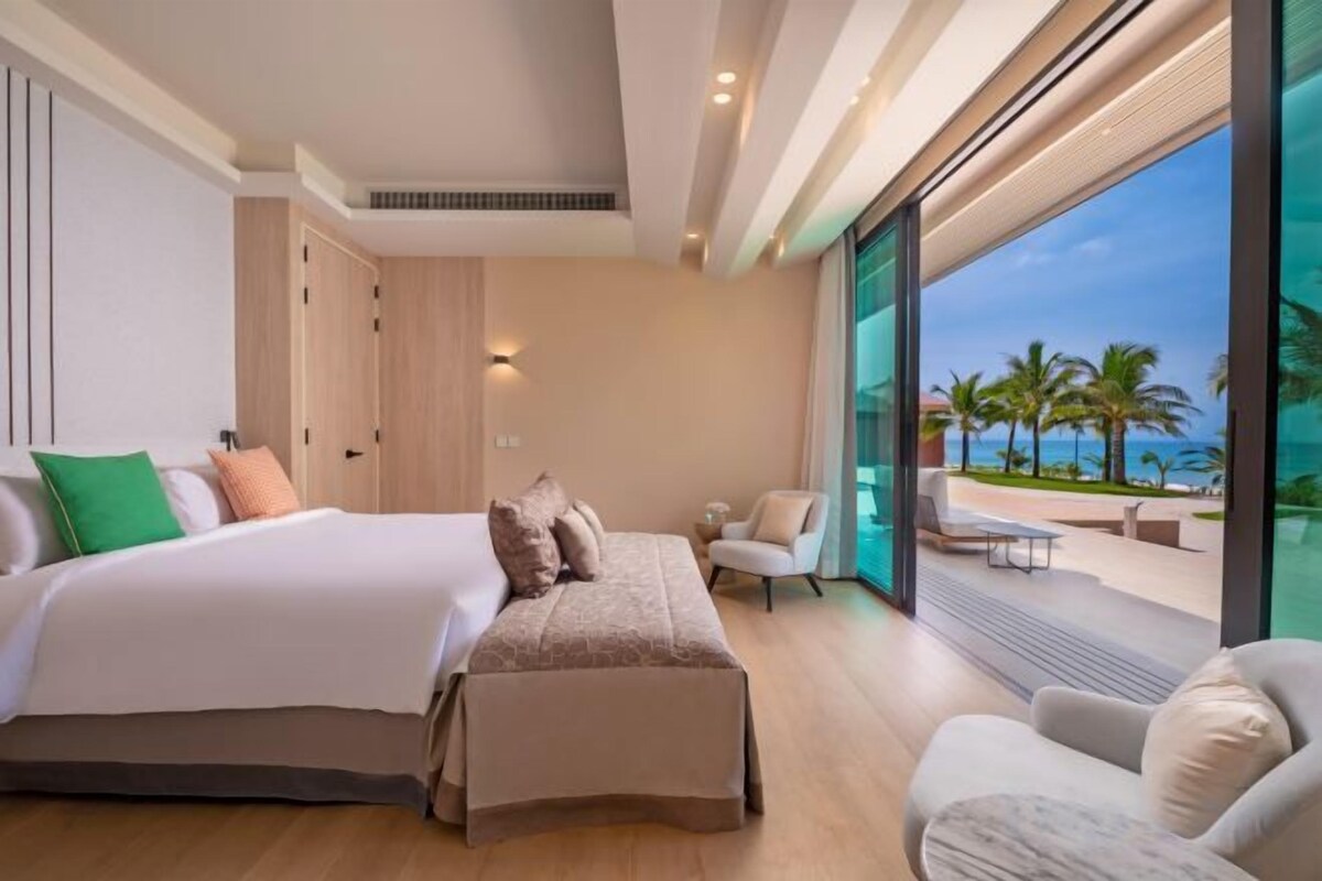 Une chambre moderne avec un grand lit, un coin salon et une vue sur la plage.