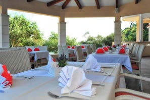 An outdoor dining area with tables set for two, featuring white tablecloths and red napkins. - Lastura Mobile Homes (Novalja)