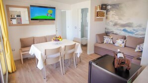 A modern living room with a dining table, sofa, and TV. - Lastura Mobile Homes (Novalja)