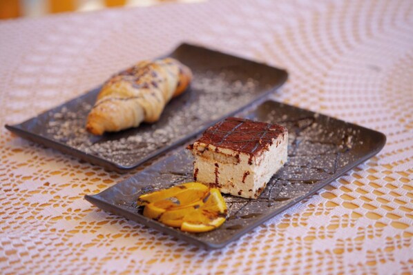 Une assiette à dessert avec une part de gâteau et un croissant, le tout posé sur une nappe en dentelle.