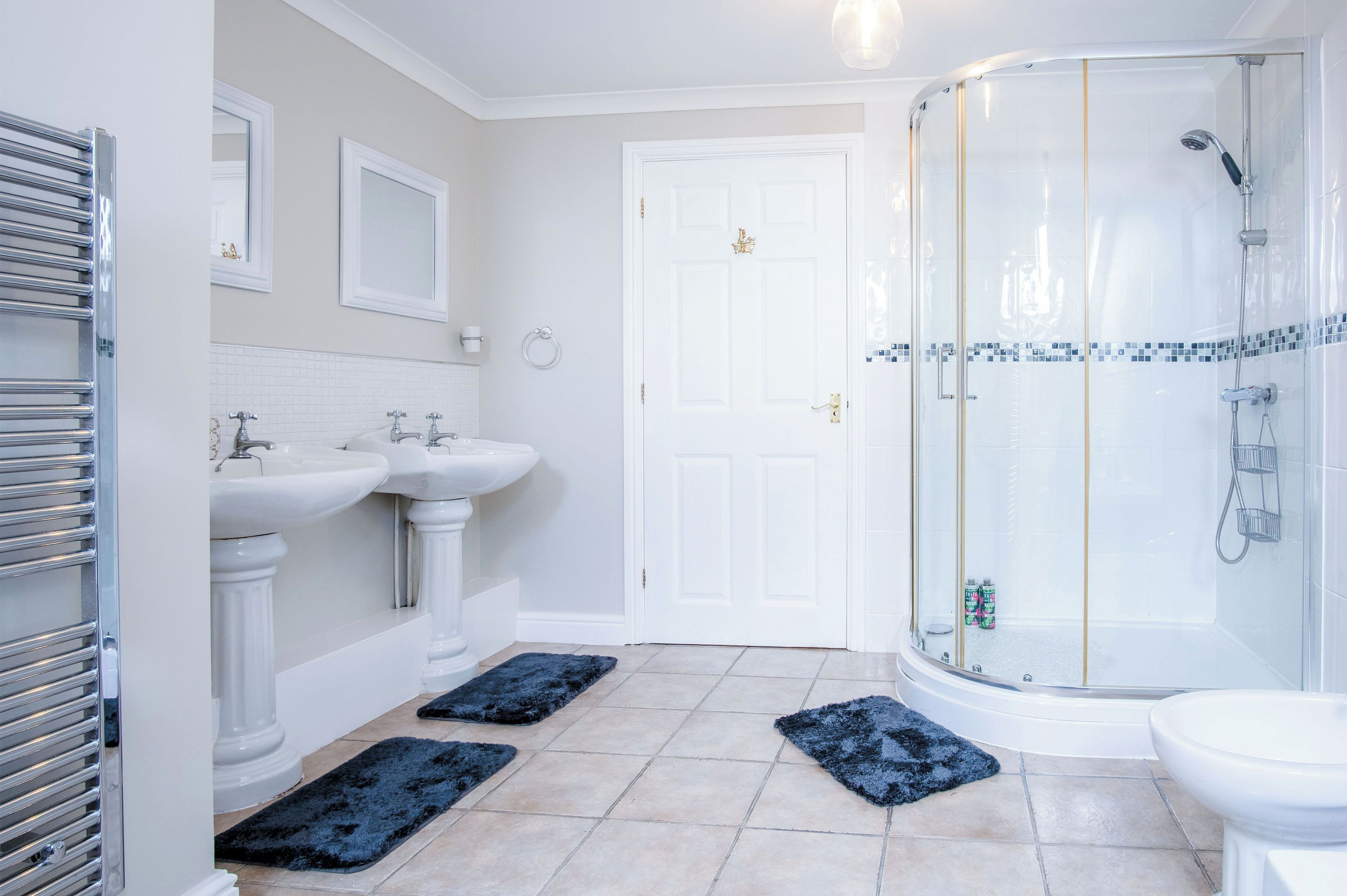 A modern bathroom with two sinks, a shower, and a toilet.