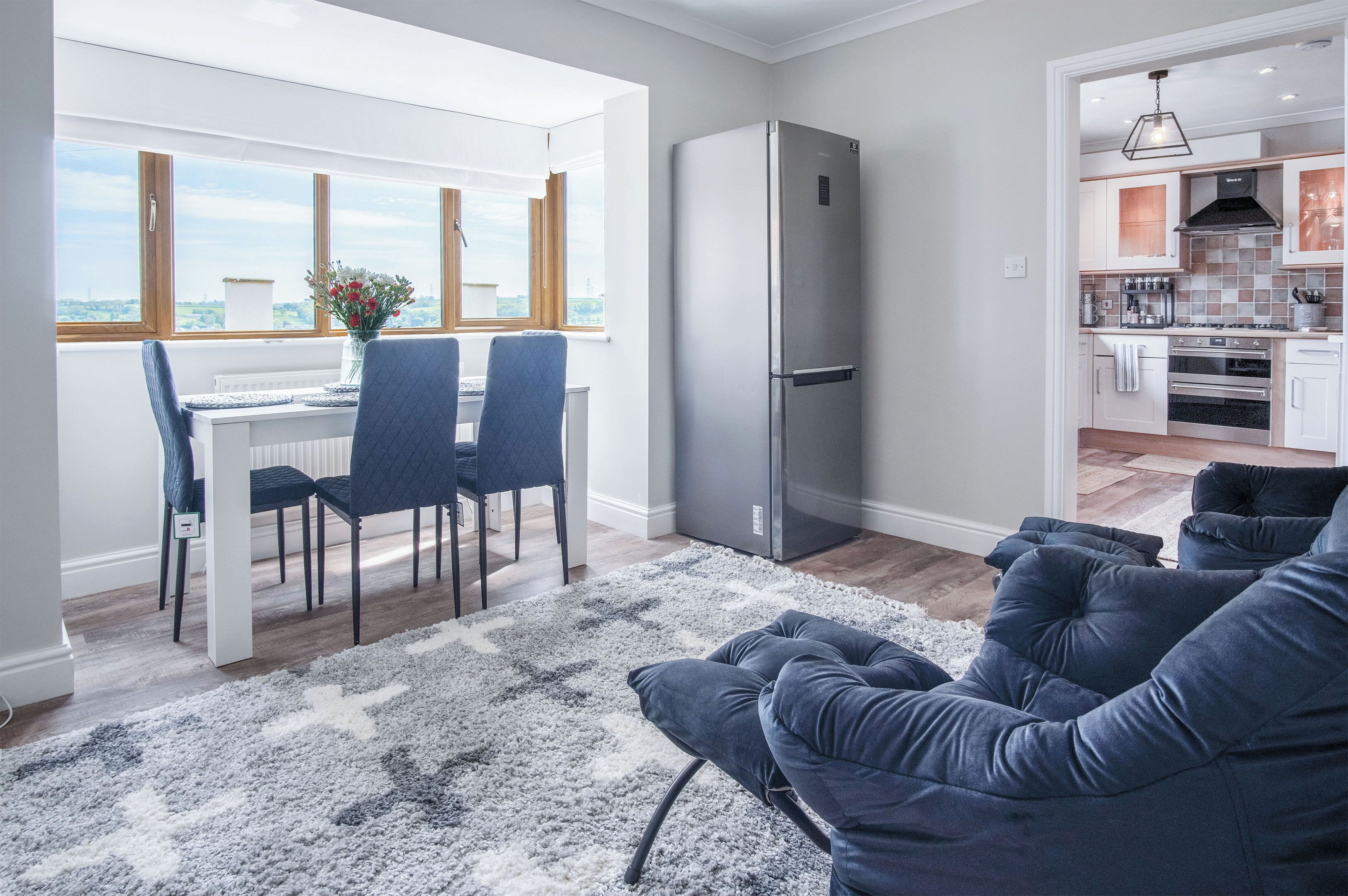Una cucina moderna con frigorifero integrato, un'area pranzo con tavolo e sedie e vista panoramica attraverso ampie finestre.
