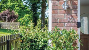 A brick wall with a number '10' sign, a metal fixture, and a wooden fence with greenery. - Sunderland Avenue - 2 Bedroom - Pembroke Dock (Pembroke Dock)