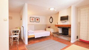 A bedroom with a bed, a desk, a chair, a television, and a fireplace. - La Rosairie - max. 2 people (Bouin)