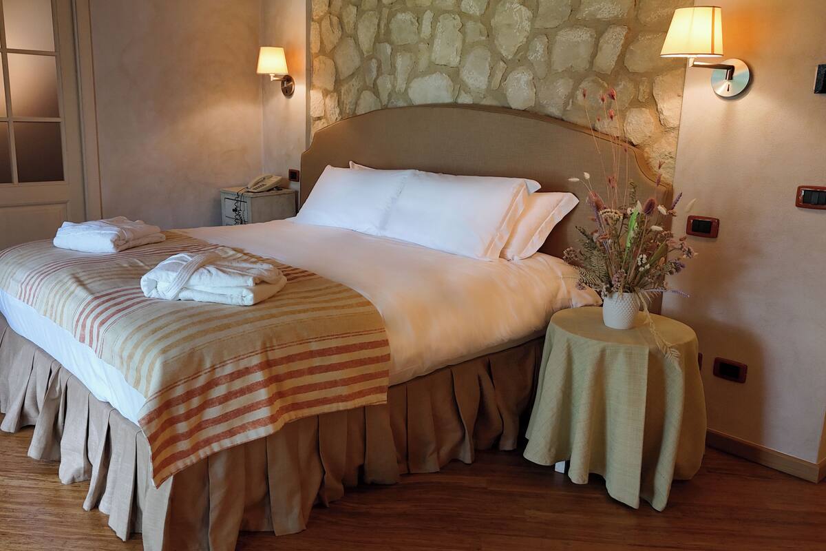 A neatly made bed with a striped bedspread and a folded towel on the side.