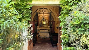A narrow stone pathway leading to an arched doorway with a religious icon above. - La Magioca (Negrar)