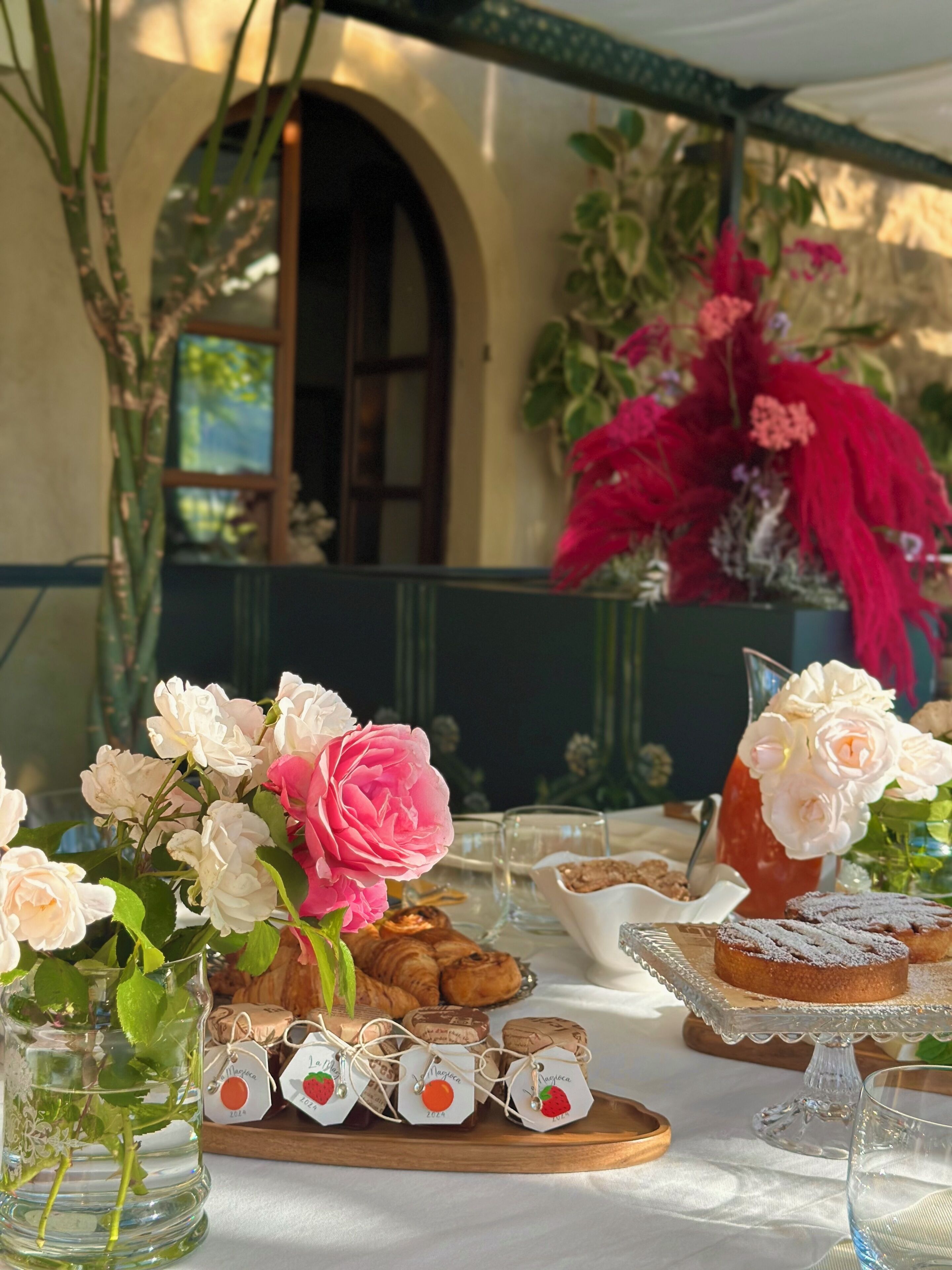 A table set with pastries, a pitcher, and a vase of flowers.