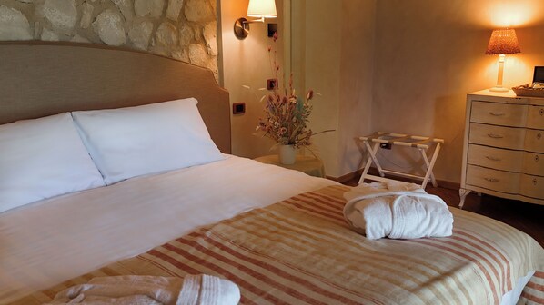 Un lit bien fait, avec des draps blancs, une couverture à rayures et deux serviettes posées sur le lit.