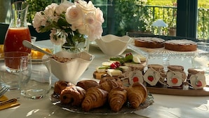 A breakfast table with croissants, pastries, and a bottle of juice, set against a scenic view through large windows. - La Magioca (Negrar)