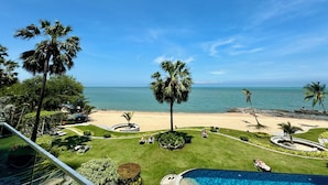 Een resort met een zwembad, palmbomen en uitzicht op het strand.