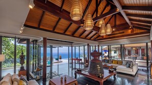 A spacious living area with a high ceiling, large windows, and a view of the ocean. - Villa La Thalé (Kamala)