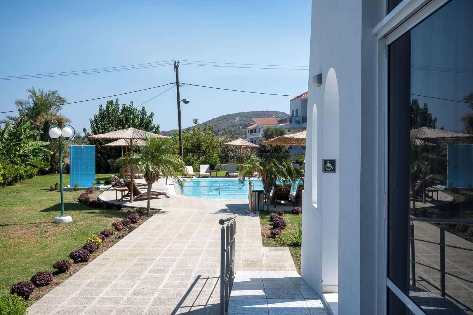 A pool area with lounge chairs, umbrellas, and a clear view of a mountain in the background.