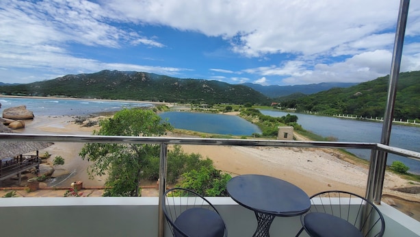 Een balkon met uitzicht op een rivier, strand en bergen.